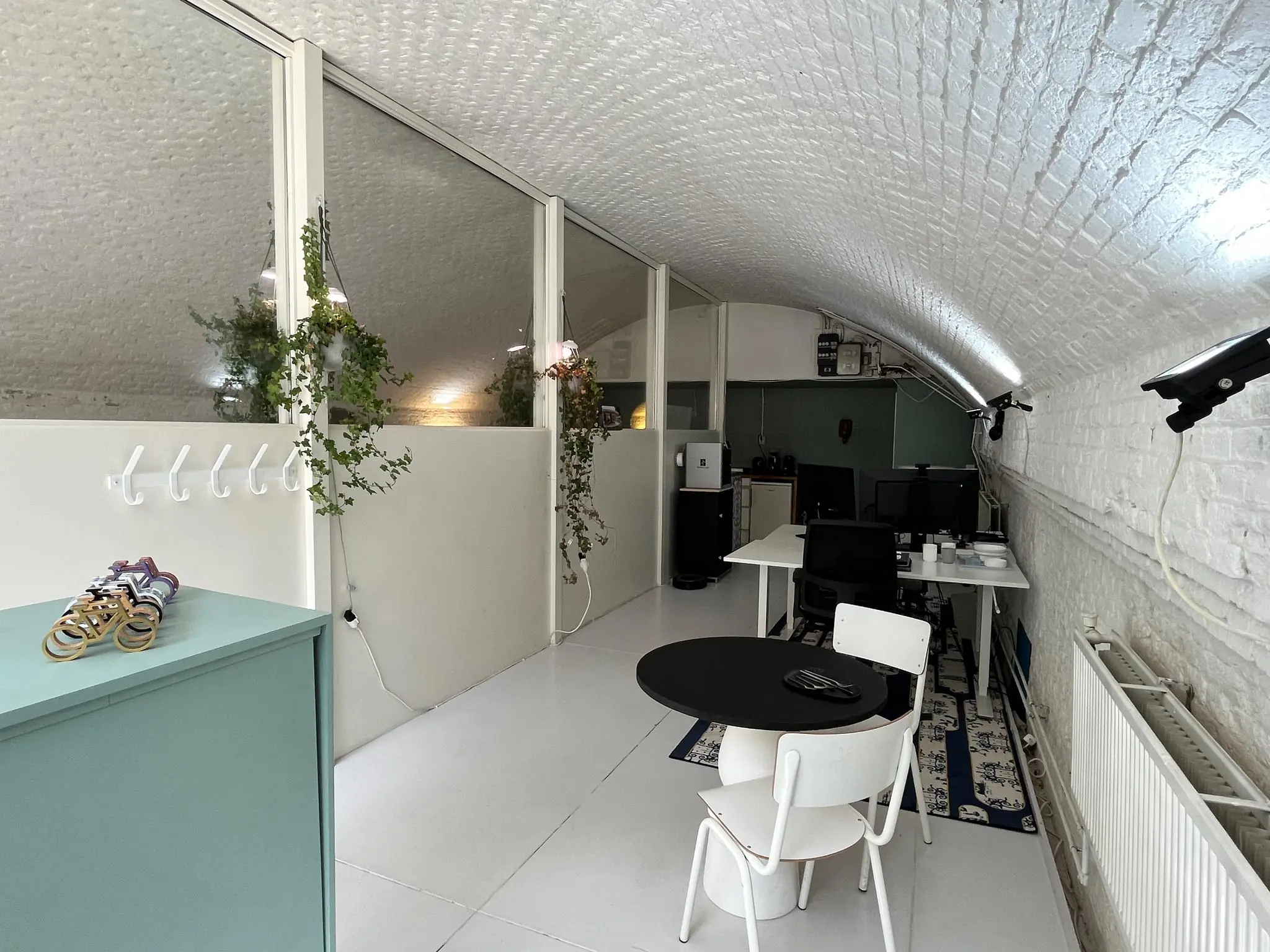 Een modern ingericht kantoor met gewelfde, witgemetselde plafonds in een ruimte genaamd 'Tussen de Bogen'.